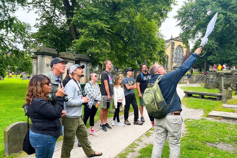Group of tourists on a walking tour with guide pointing at landmarks in Edinburgh