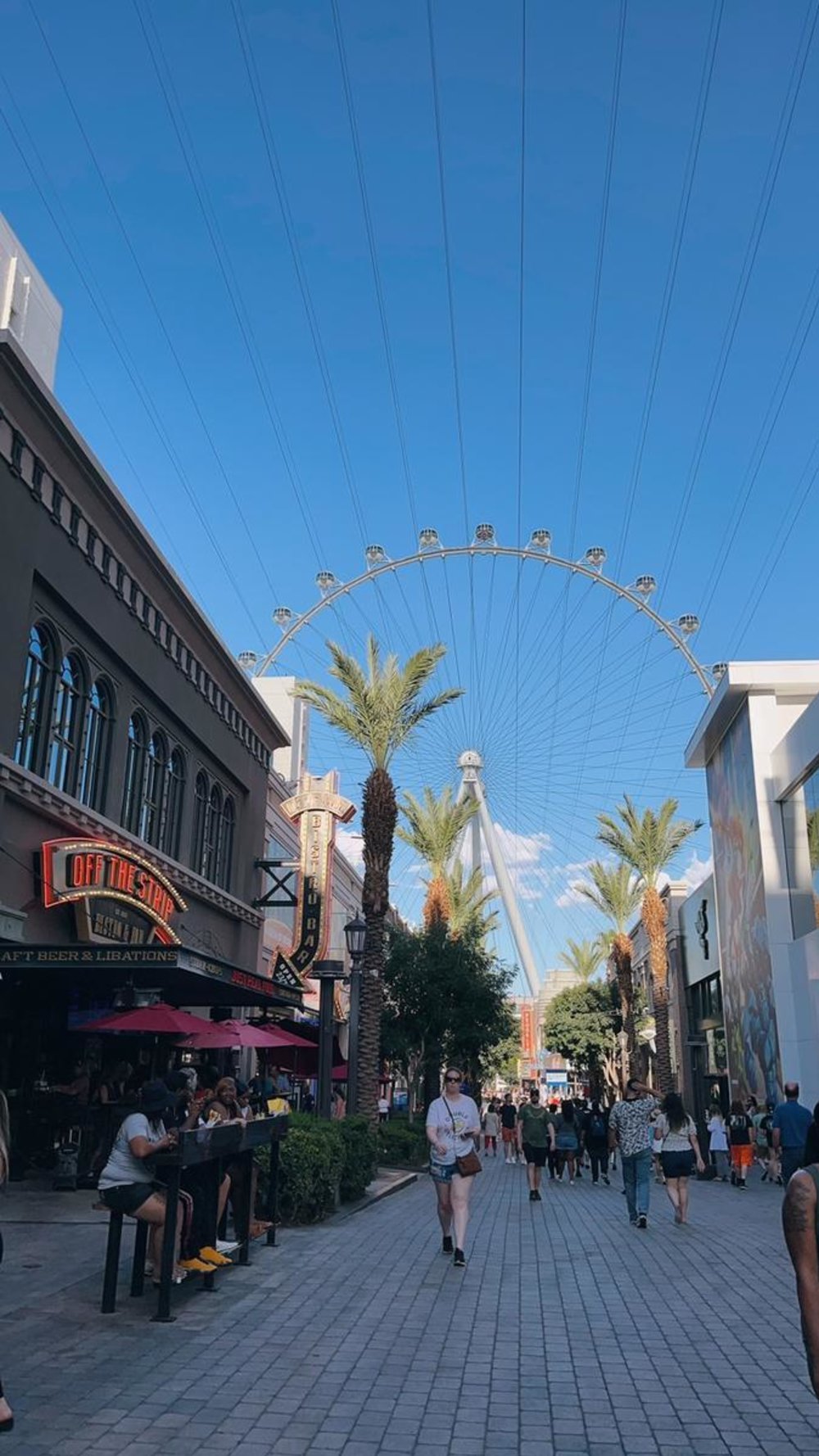 Crowd walking at LINQ Promenade with Las Vegas Ferris Wheel in background