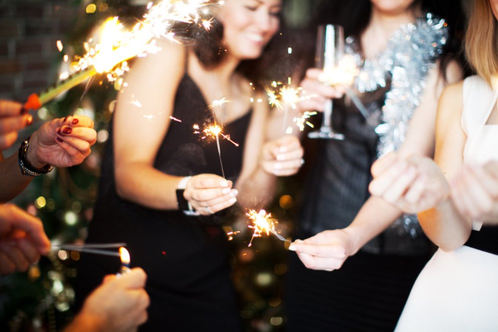 shot of people holding up sparklers and glasses celebrating new years eve