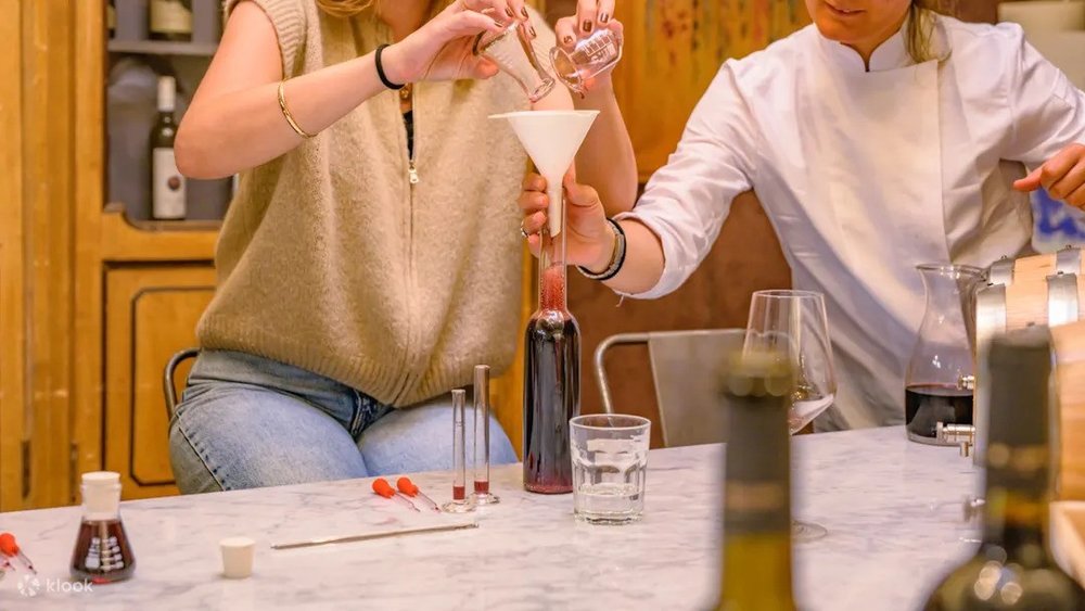 Two people blending red wine into a bottle during a wine mixing class in Florence