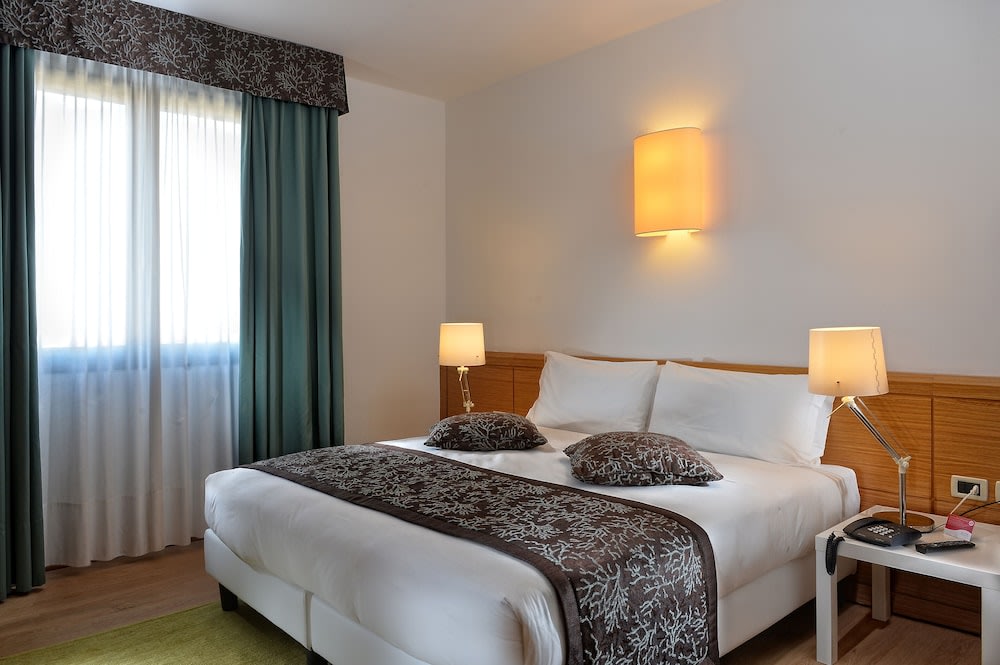 A spacious and well-made bed in one of the Elite Hotel Mestre Venice’s modern rooms