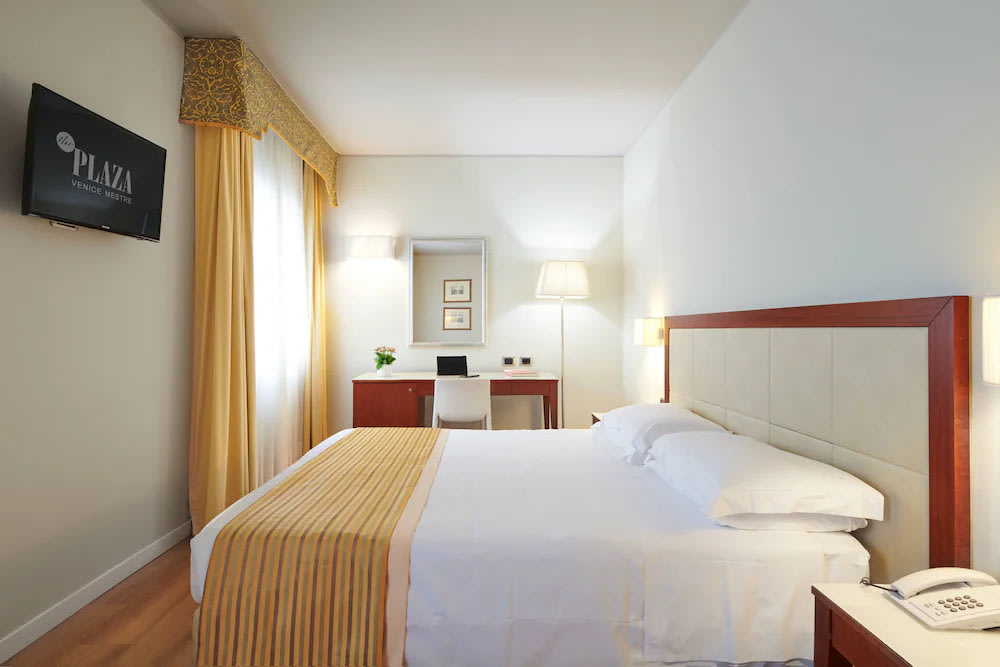 Crisp white sheets and a sunlit room in Hotel Plaza Venice