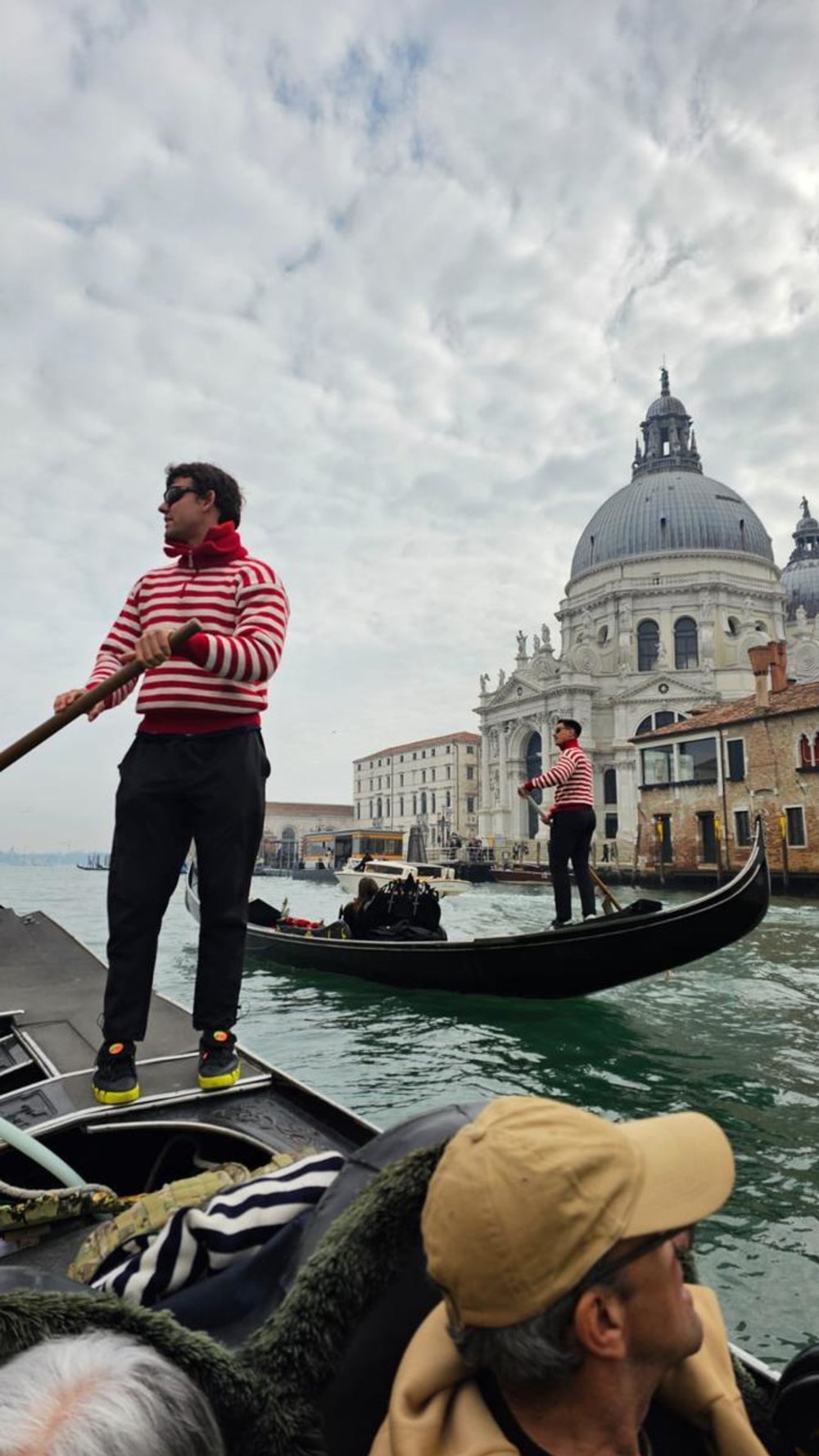 Gondola ride on Venice’s Grand Canal with gondoliers in red stripes near basilica