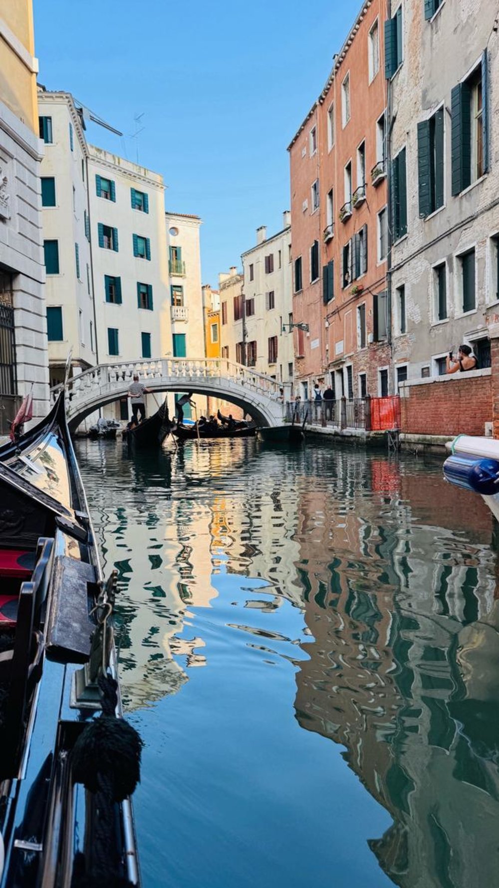 Gondolas under a stone bridge in a colorful Venice canal