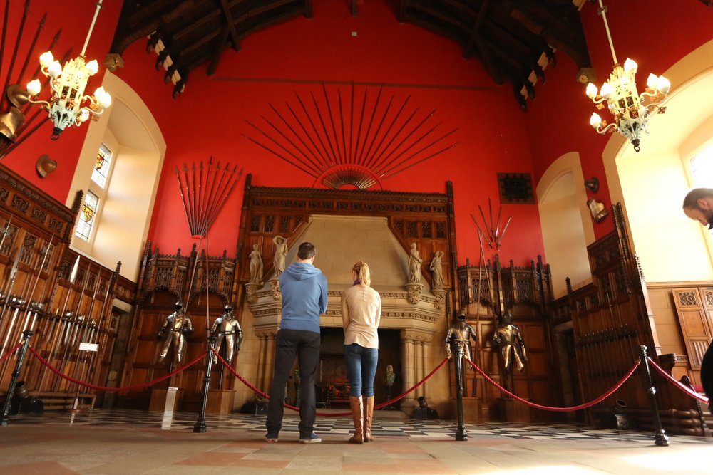 Visitors viewing armor and ornate fireplace in Edinburgh Castle’s Great Hall