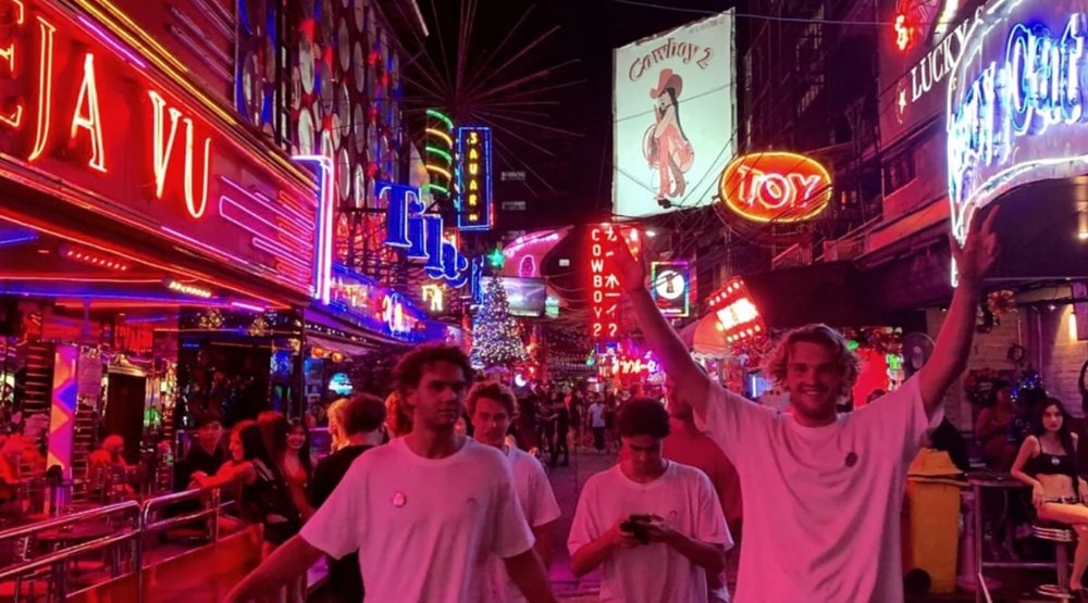 group of four men hanging out walking the streets of bangkok at night