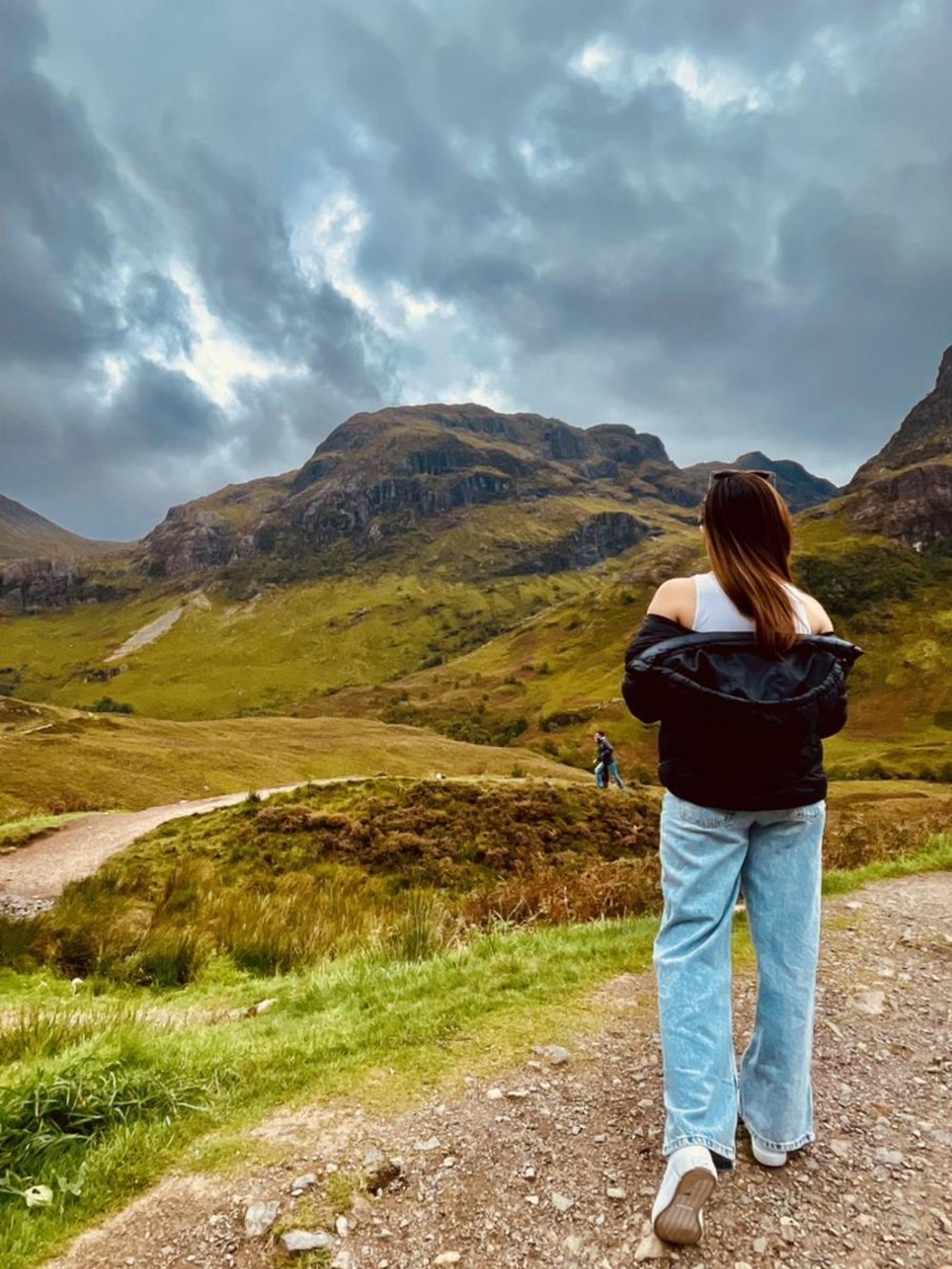 Traveler looking at Glencoe’s rugged mountains under moody Scottish skies.