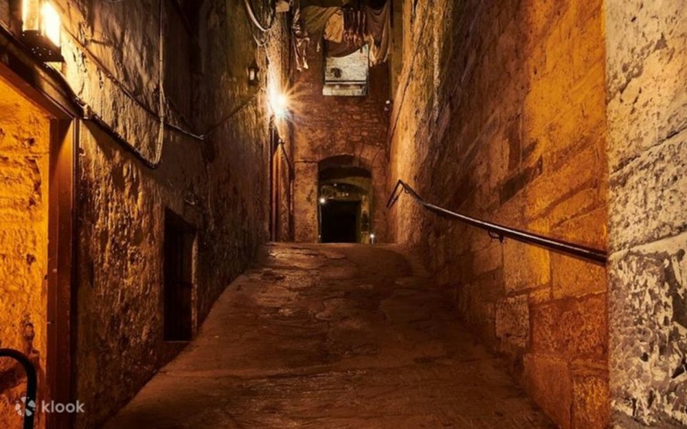 A dimly lit, narrow, and ancient underground alleyway
