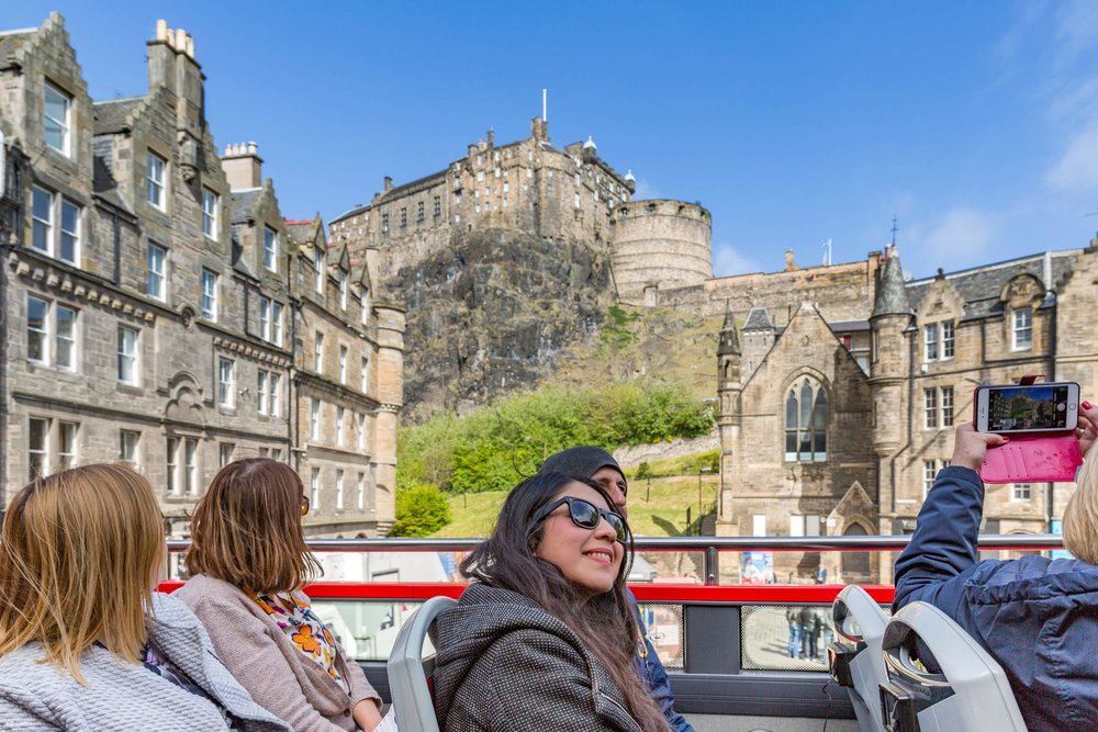 A group of people on the upper deck of an open-top sightseeing bus