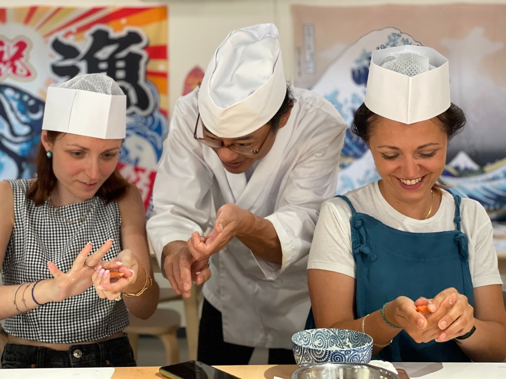 A Japanese chef teaching two women how to cook.