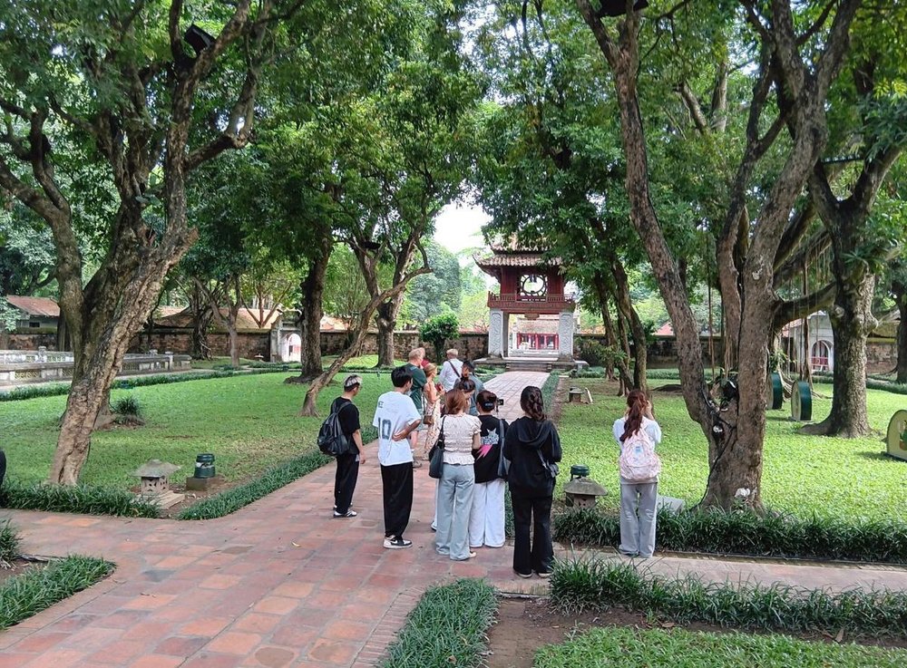 Group of tourists walking in the green courtyard at Temple of Literature Hanoi