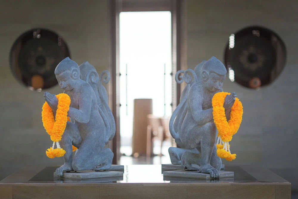 Symmetrical monkey statues adorned with yellow floral garlands