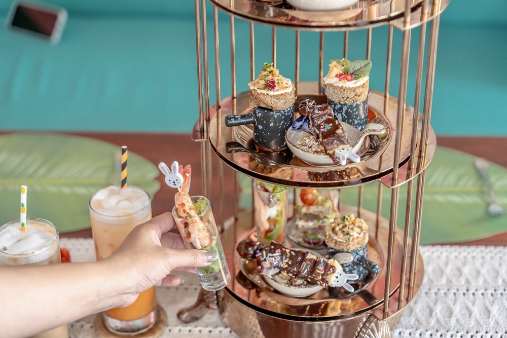 A hand holding one of the afternoon tea snacks at KOA Dining