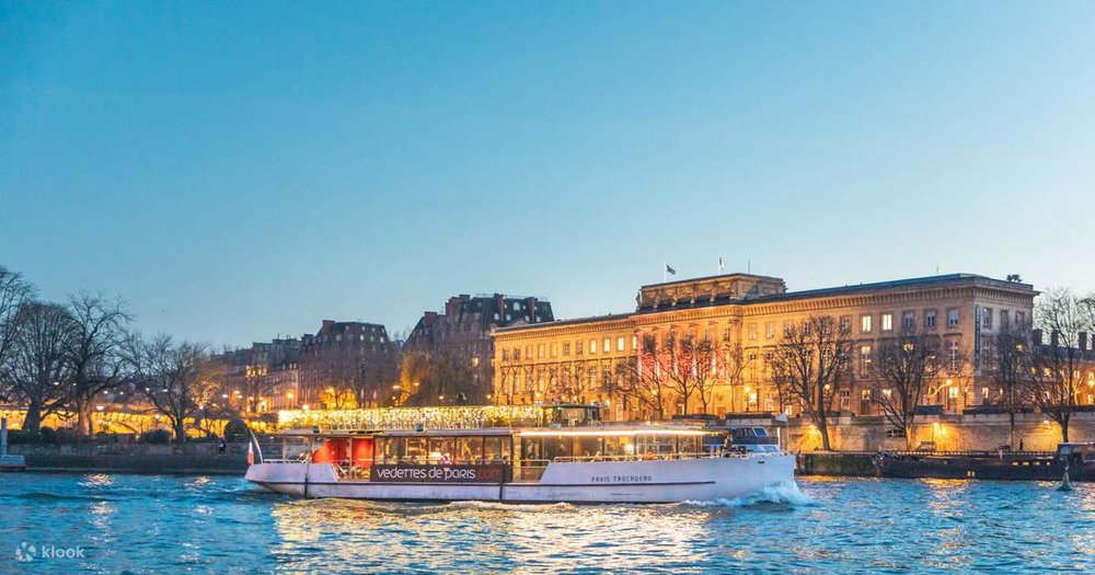 A Vedettes de Paris boat cruising along the Seine River in Paris at dusk