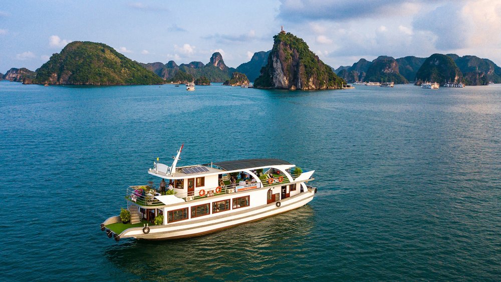 Cruise ship gliding across Halong Bay surrounded by limestone islands