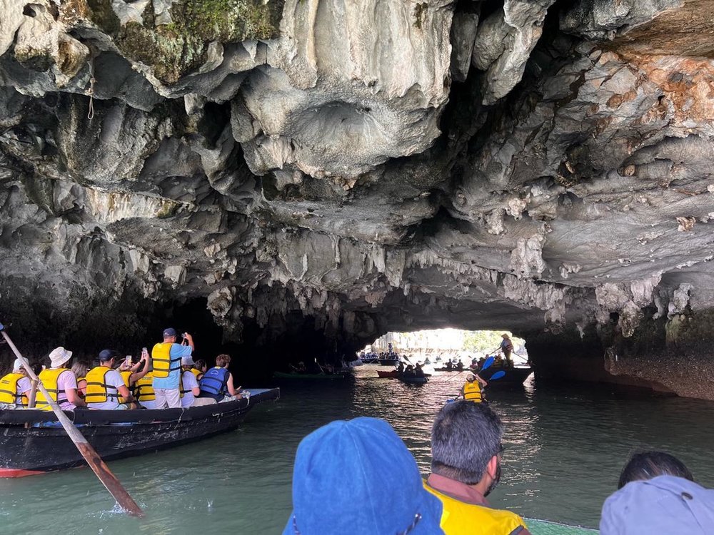 Tourists kayaking through limestone cave tunnel at Hang Luon in Halong Bay