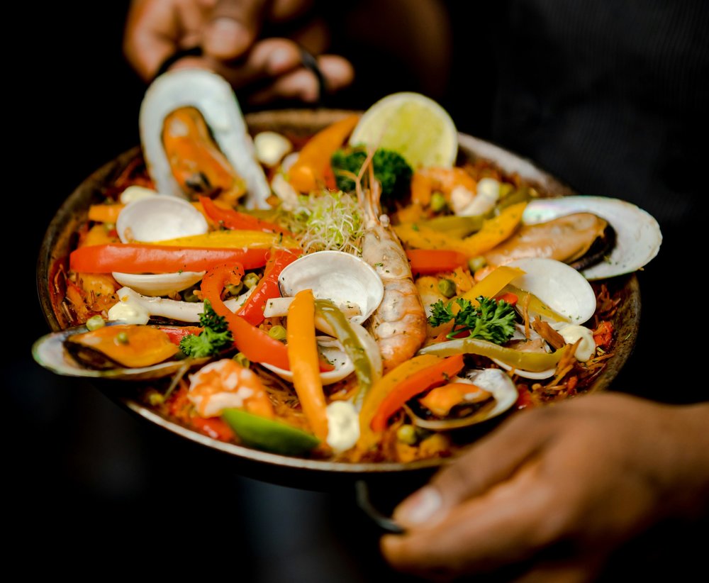 Paella served in a small pan with fresh seafood and veggies