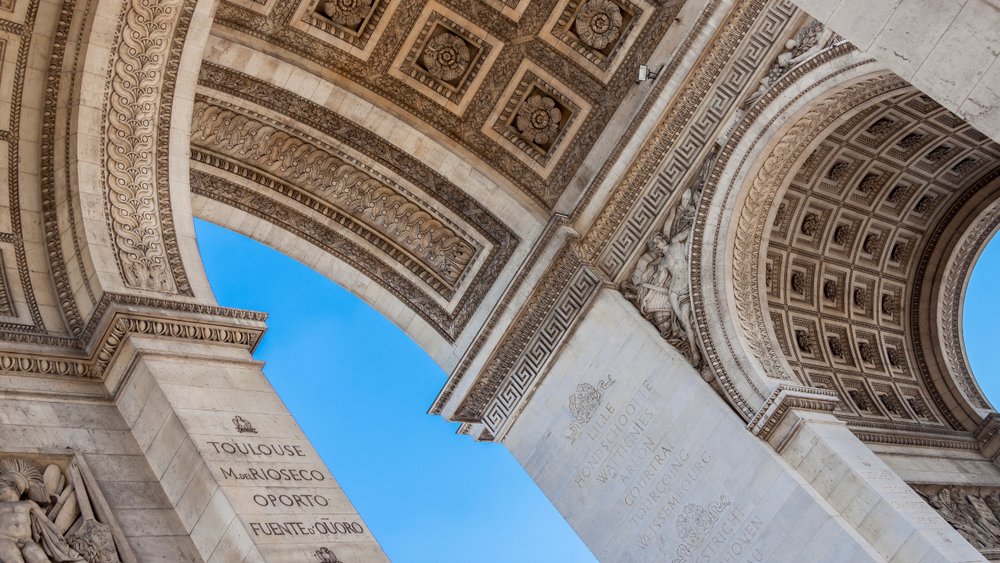 Close-up of the Arc de Triomphe’s detailed stone carvings against a blue sky