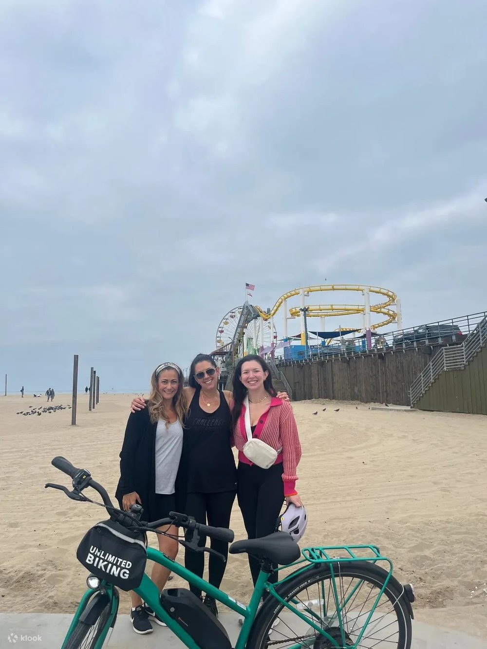 Group of friends biking near Santa Monica Pier on a cloudy morning.