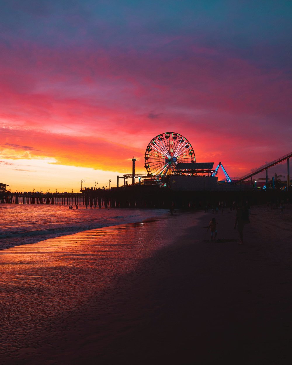 Santa Monica Pier Ferris wheel glowing at sunset over the Pacific Ocean.