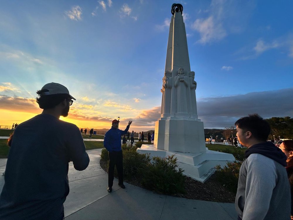 Visitors admiring the Astronomers Monument at Griffith Observatory during sunset