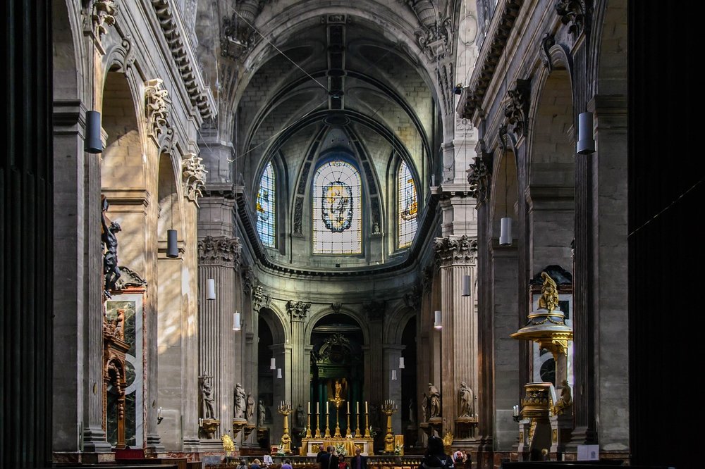 Stained glass windows, gilded statues, and the altar of The Church of St. Sulpice