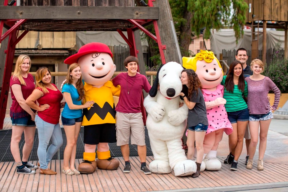 Visitors posing with Snoopy and Peanuts characters at Knott’s Berry Farm.