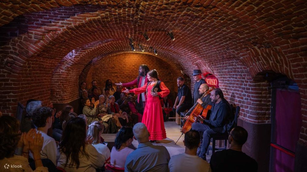Inside a brick cave, artists perform a flamenco while the audience sits around them