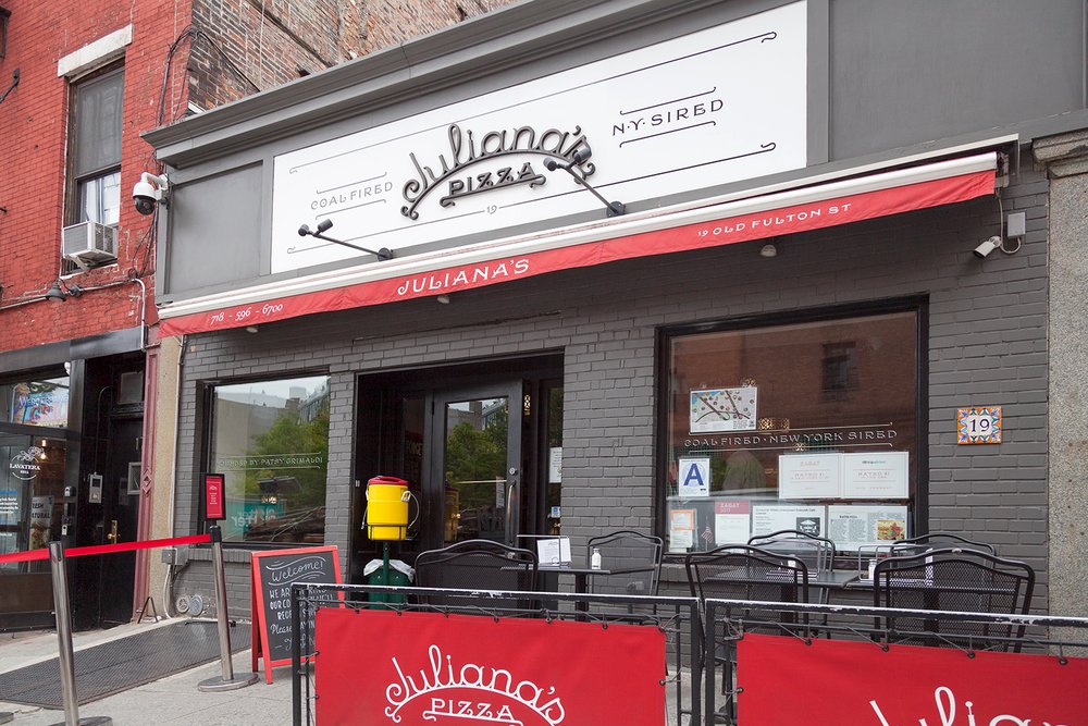 Exterior view of Juliana’s Pizza with red awning and outdoor seating