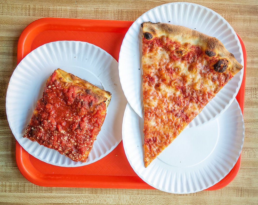 Two New York pizza slices on paper plates, one square and one classic round