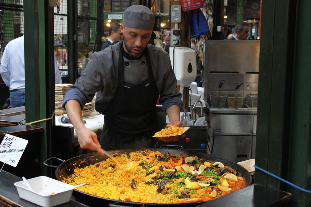 Man cooking paella in a public market.