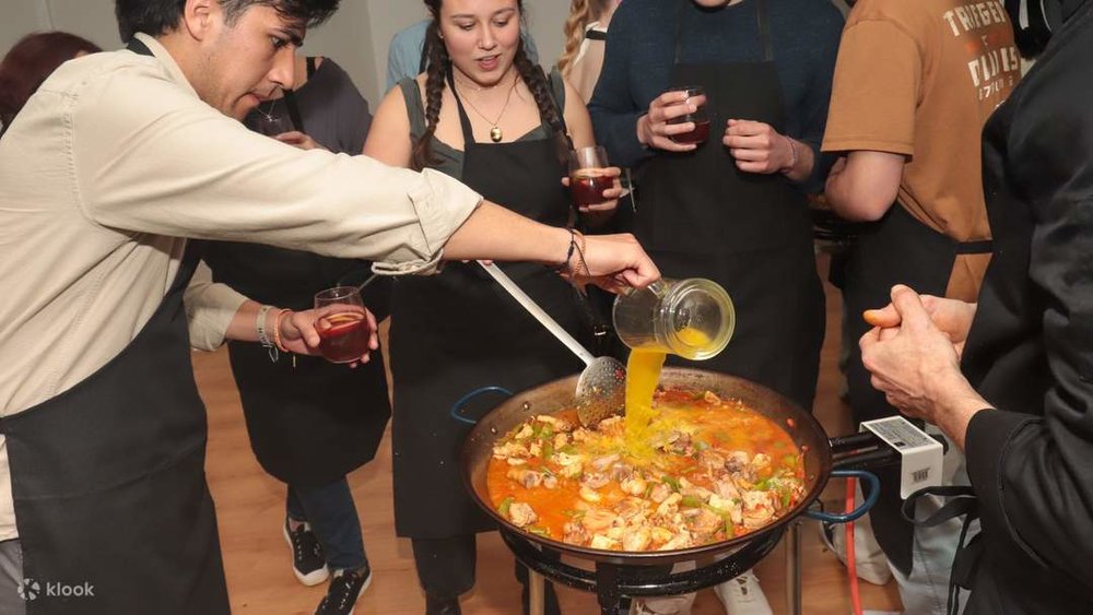 A chef teaching students how to make paella.