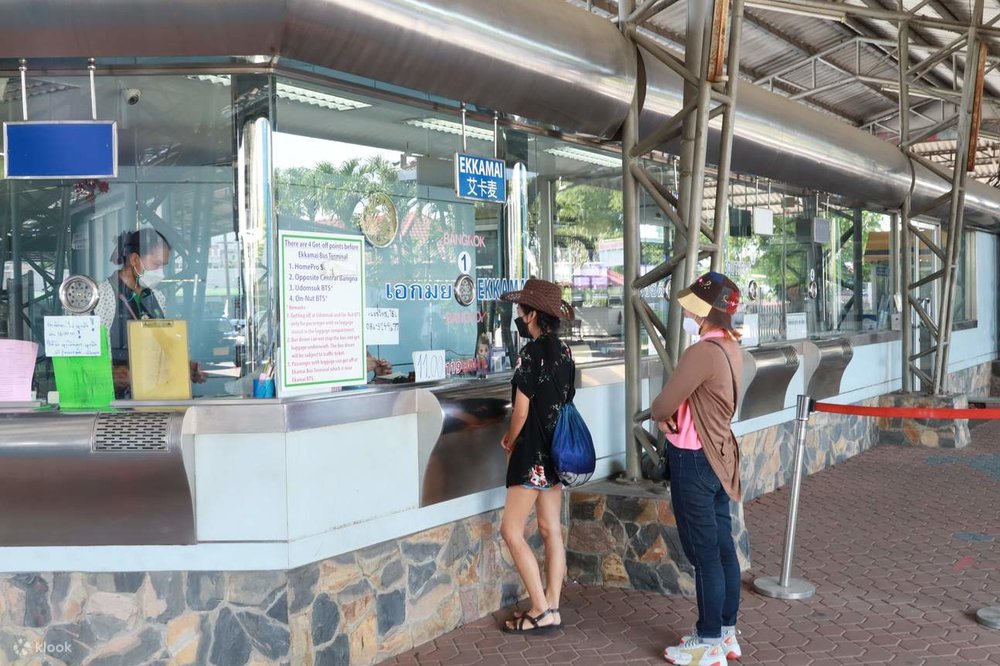 Two women lining up in front of the ticket counter at the Ekkamai Bus Terminal
