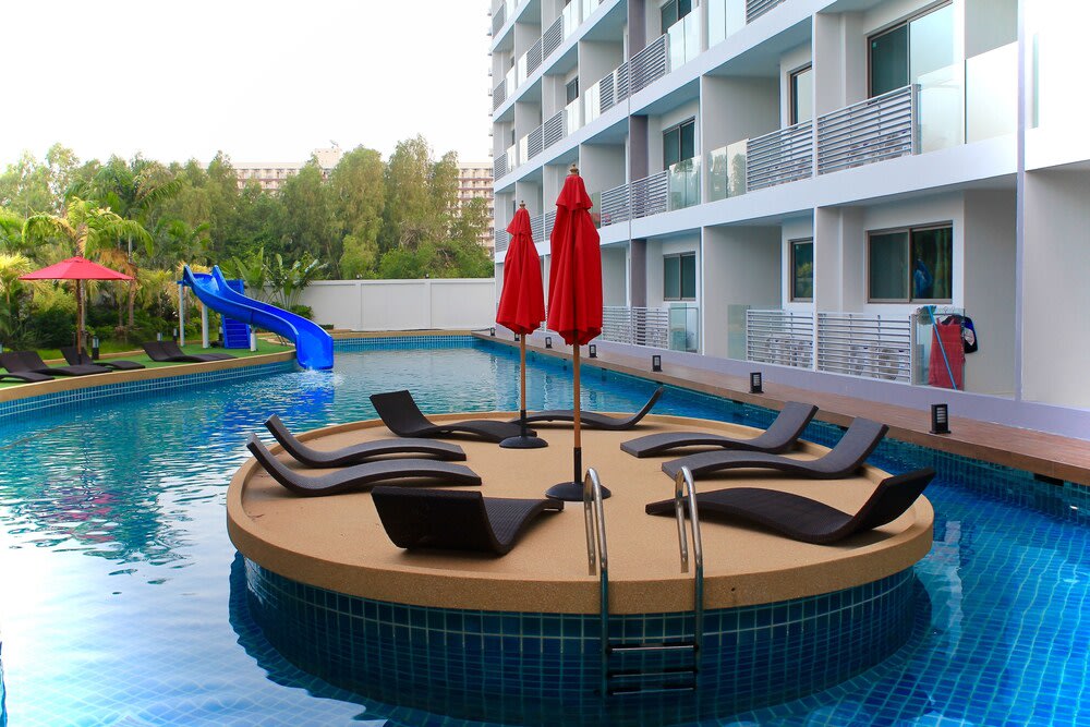An elevated circular portion with sunbeds stands in the middle of the swimming pool.