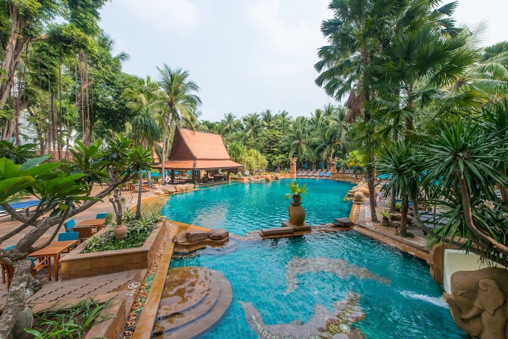 Avani’s swimming pool is bordered by palm trees and traditional Thai architecture.