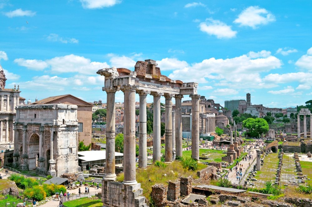 The Roman Forum ruins with visitors exploring under bright spring skies