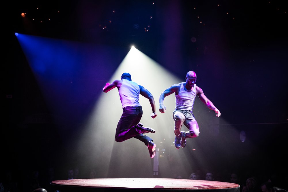 Two acrobats performing a jump stunt onstage at Absinthe Las Vegas.