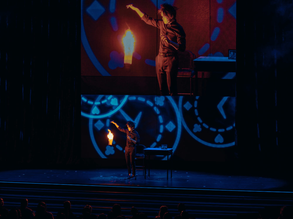 Magician performing a fire illusion onstage at a Las Vegas magic show.