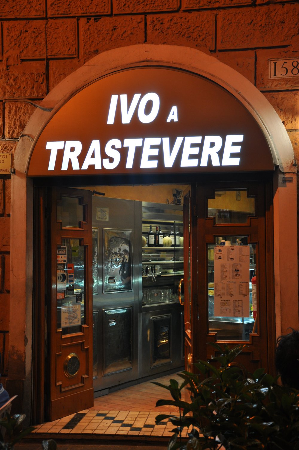 Front entrance of Ivo a Trastevere pizzeria at night in Rome.