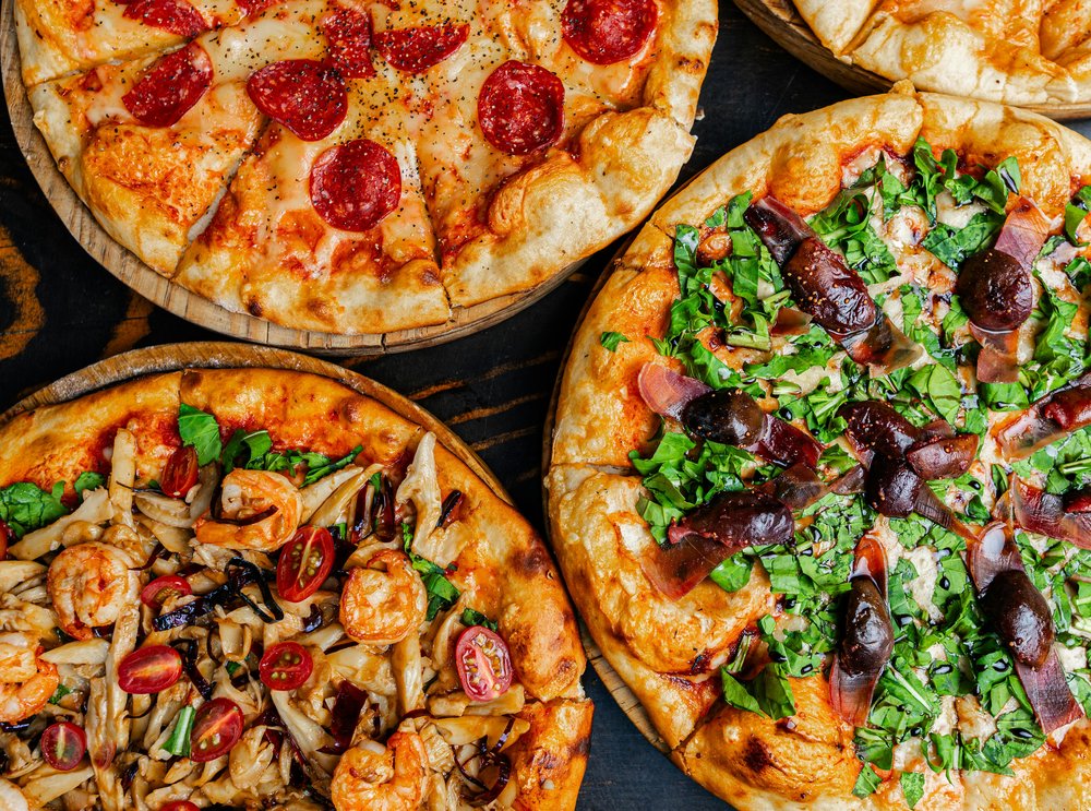 Assorted gourmet pizzas with pepperoni, greens, and shrimp.