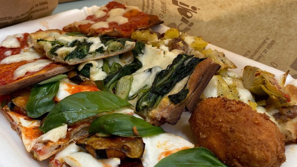 Assorted Roman pizza slices with fresh basil and toppings.