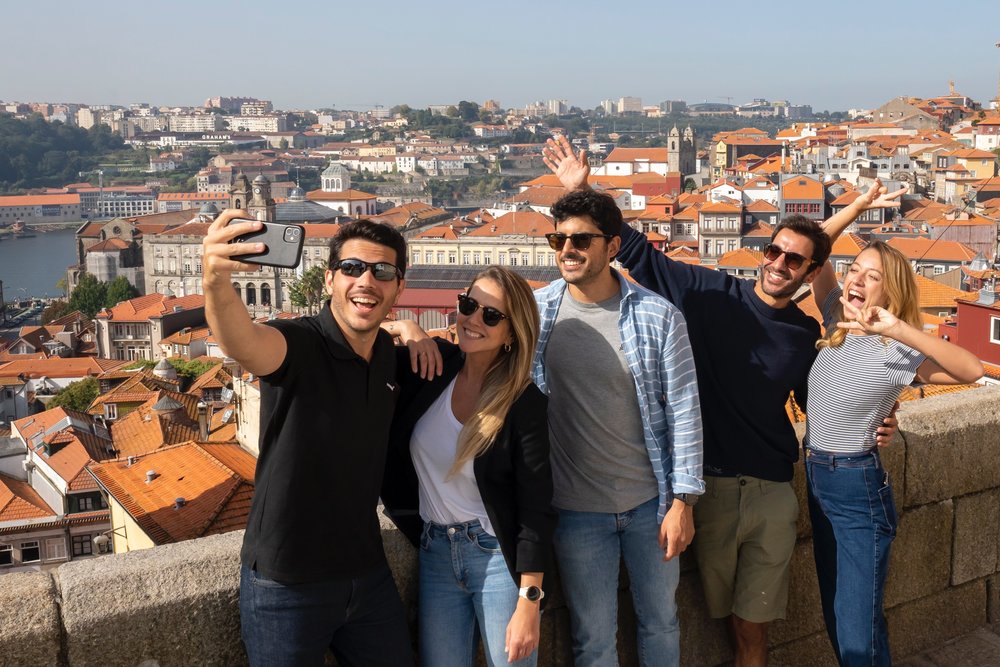 Alt-Text: Group of travelers taking a selfie with Porto’s skyline in the background.