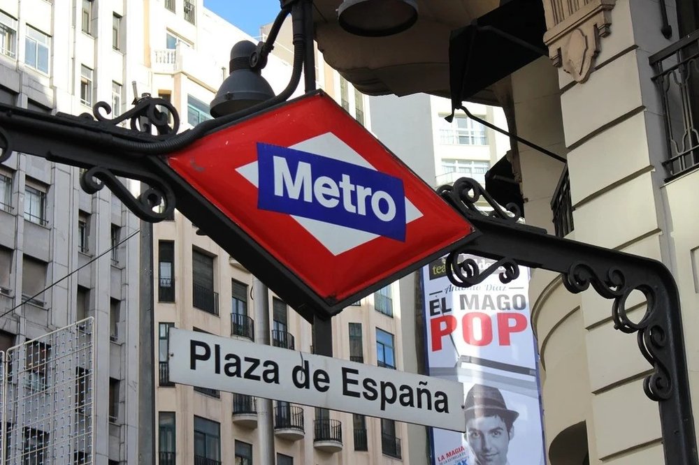 Plaza de España metro sign hanging from the side of a building