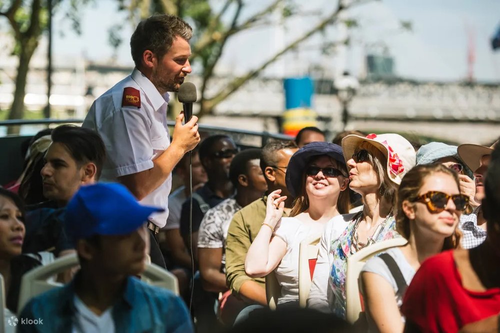 Tour guide speaking to passengers on an open-top sightseeing bus in Madrid