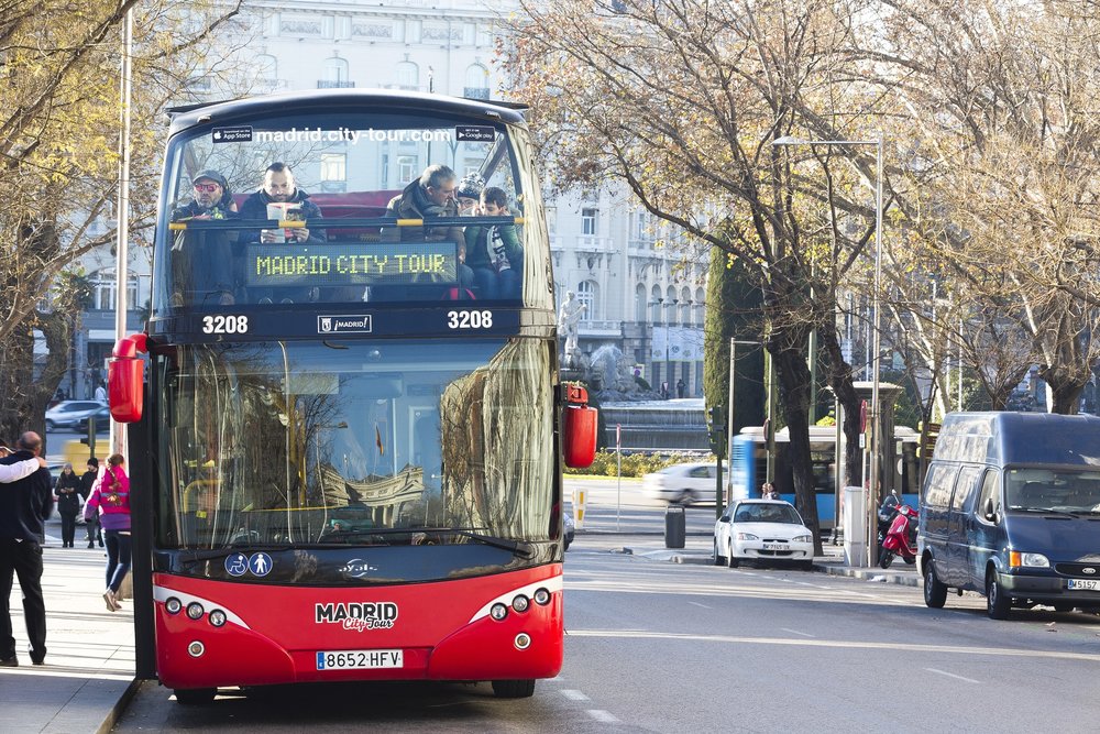 Red Madrid City Tour double-decker bus on the street near historic buildings
