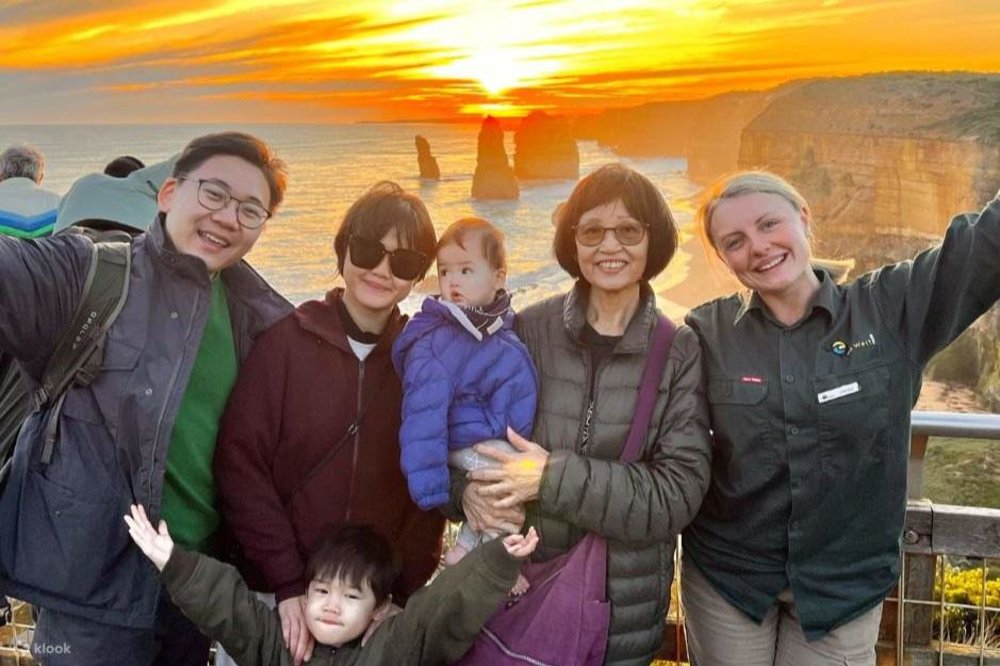 A family posing in front of a sunset behind the 12 Apostles