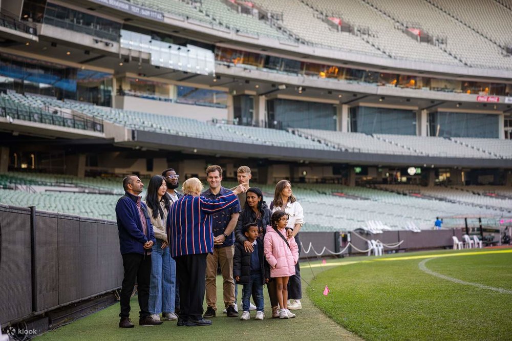 A group of tourists and a guide on the MCG Stadium lawn