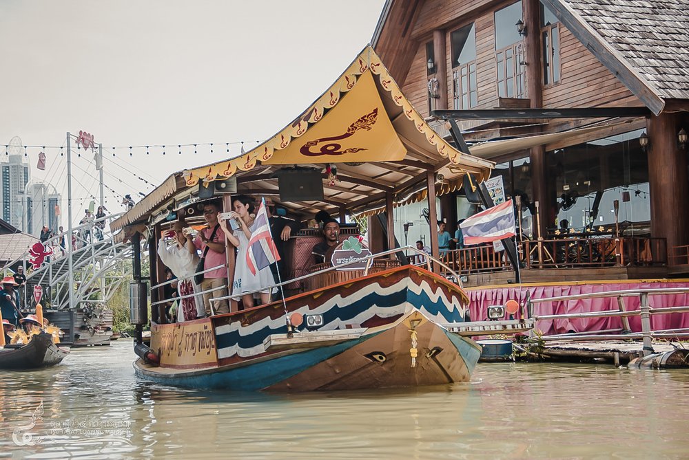 Visitors taking photos aboard a wooden boat at Pattaya Floating Market