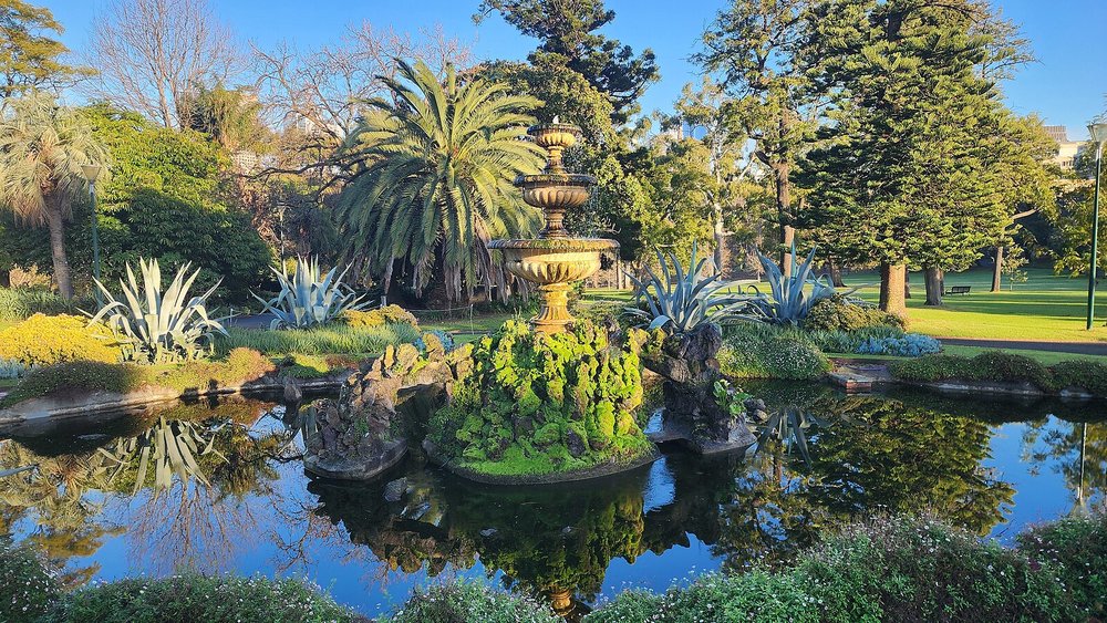 Historic Fitzroy Gardens fountain reflected in a peaceful pond