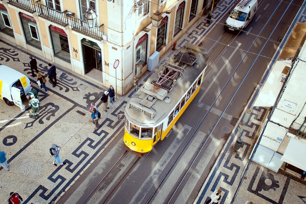Yellow Lisbon tram seen from above on mosaic sidewalks in Baixa district